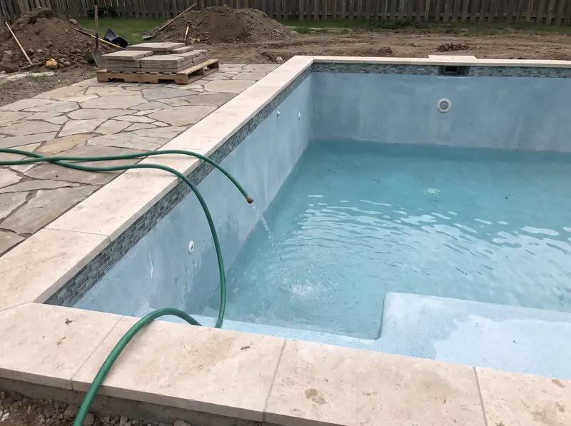 New pool being filled with a garden hose, coping and tile done